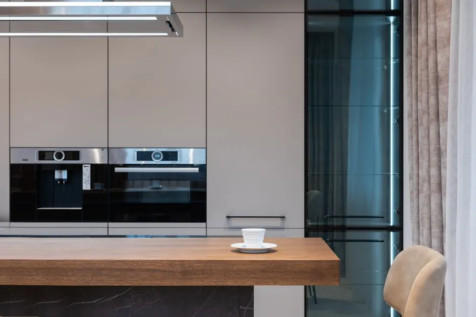 Modern room with kitchenware and counter with coffee cup near chairs and curtains with cabinet and oven